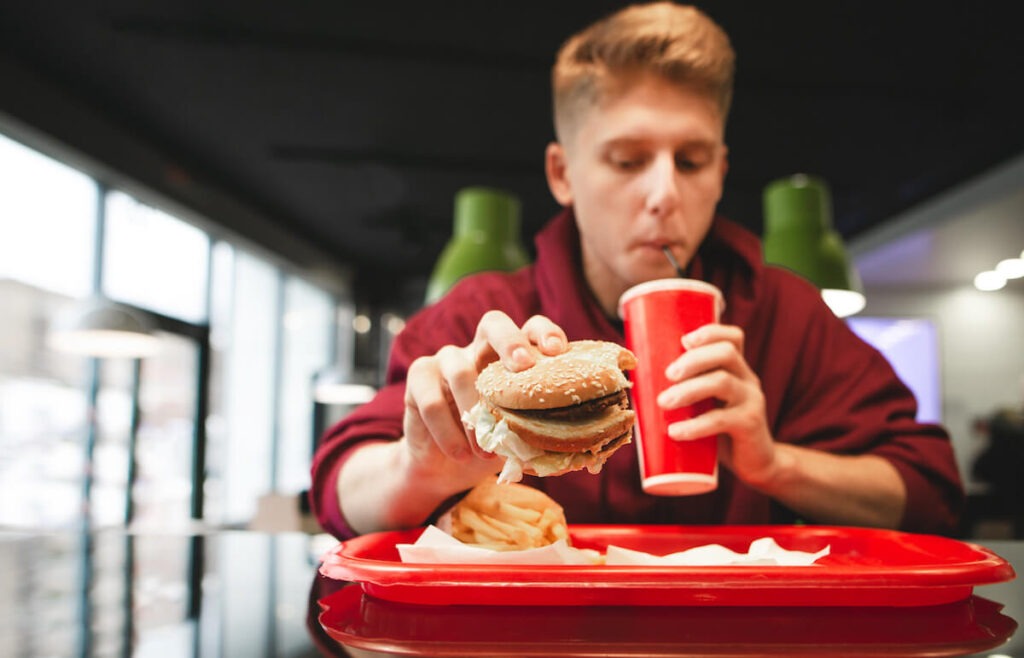 Restaurant AI: man taking a sip of his drink while grabbing a burger