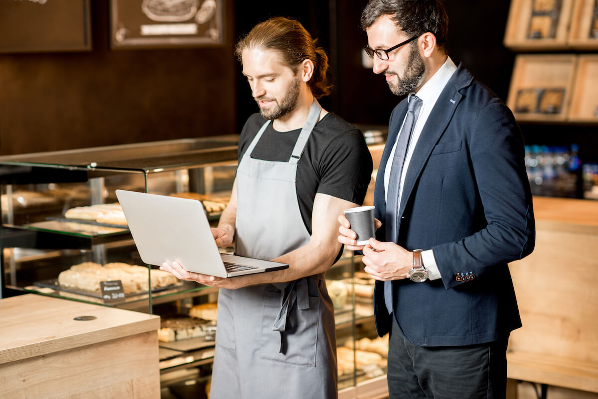 Manager and waiter looking at a laptop